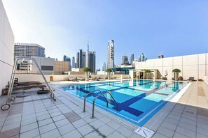 A rooftop swimming pool with a city skyline in the background.