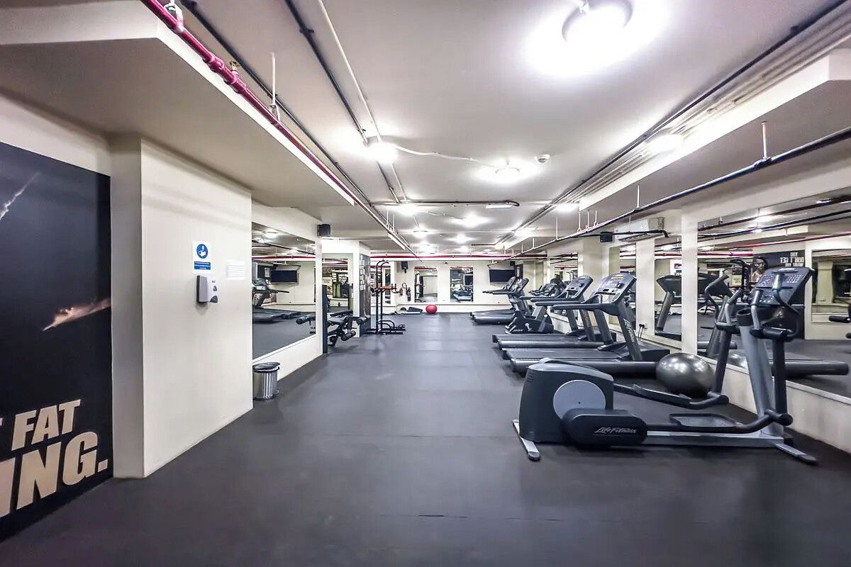 Un gimnasio con cintas de correr, elípticas y pesas libres.