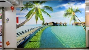 Une fresque murale représentant un paysage de plage tropicale, avec des palmiers et des bungalows sur pilotis.
