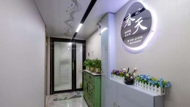 Un couloir avec un comptoir d’accueil, une armoire verte et un panneau mural affichant des caractères chinois.
