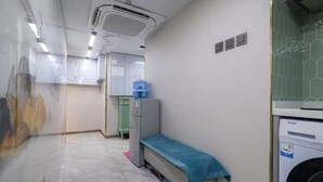 Une chambre d’hôtel avec un lit, une machine à laver, une petite table et un placard.