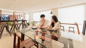 Un interior moderno con una mesa de vidrio, sillas de madera y un ventanal grande.