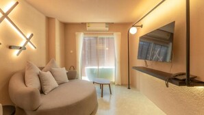 Una sala de estar moderna con un sofá curvo, una mesita y un televisor montado en la pared.