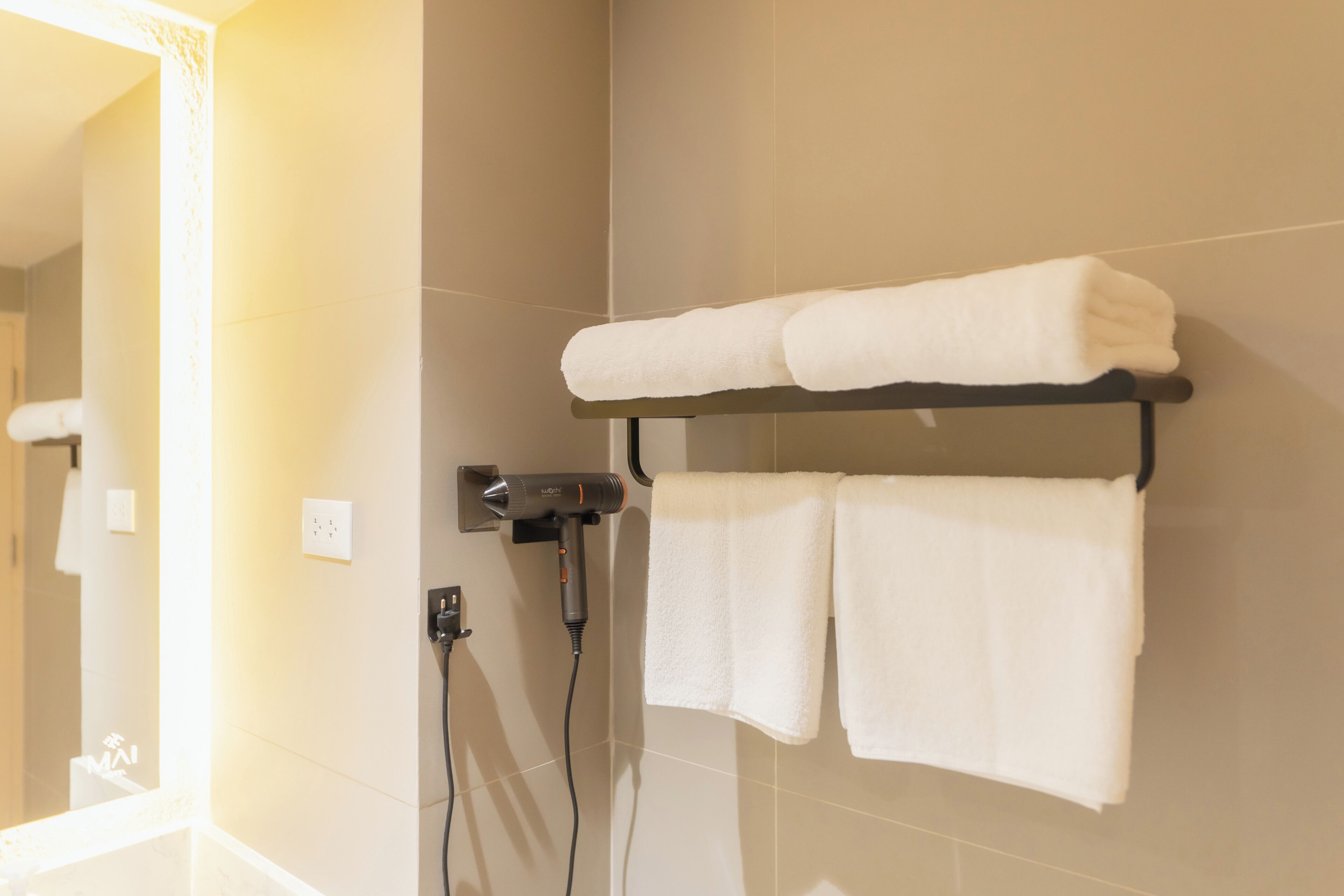 A bathroom with a towel rack holding two towels, a hairdryer, and a mirror.