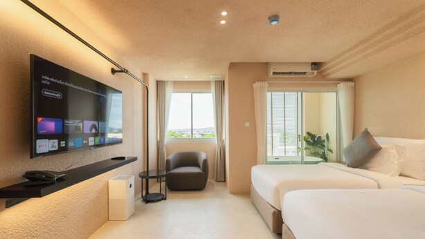Habitación de hotel con televisión en la pared, un sofá, una cama y una ventana con vistas.