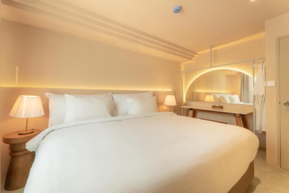 A hotel room with a large bed, two bedside tables with lamps, a mirror, and a door.