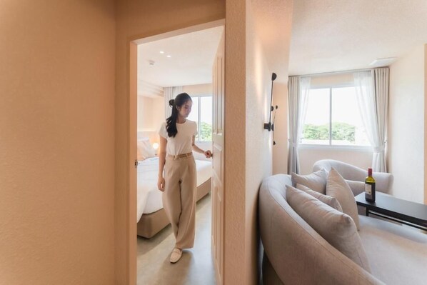Una habitación de hotel con cama, sofá y una mesa con una botella.
