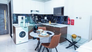 A modern kitchen with a glass dining table, a built-in washer, and a microwave. - Bloomfields Hidden Gem Studio In Arjan (Dubai)
