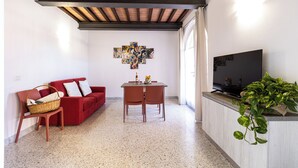 A living room with a red sofa, a wooden dining table, and a television.
