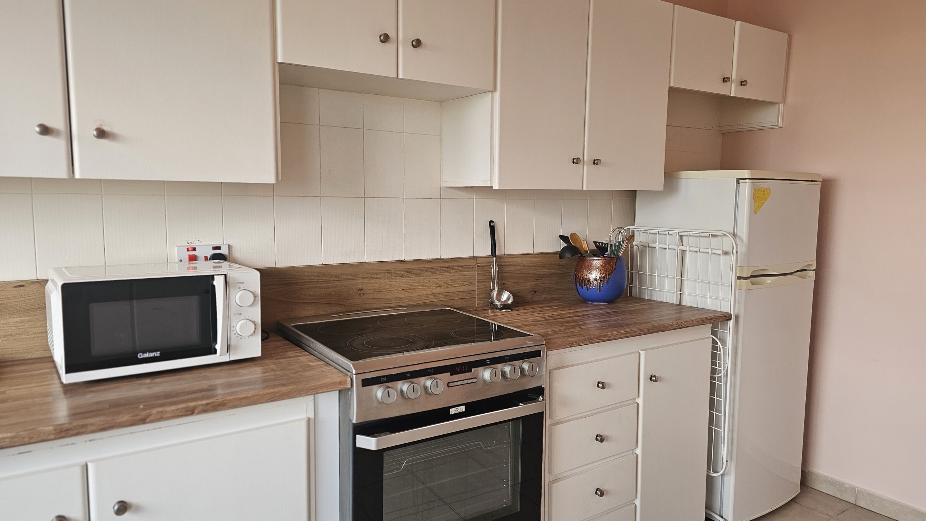 A kitchen with white cabinets, a microwave, a stove, and a refrigerator.