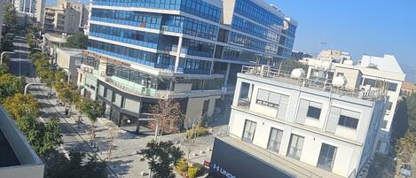 Eine moderne Stadtstraße mit einem markanten, gebogenen Gebäude und einem Geschäftsgebäude mit einem 'Under Armour'-Schild.