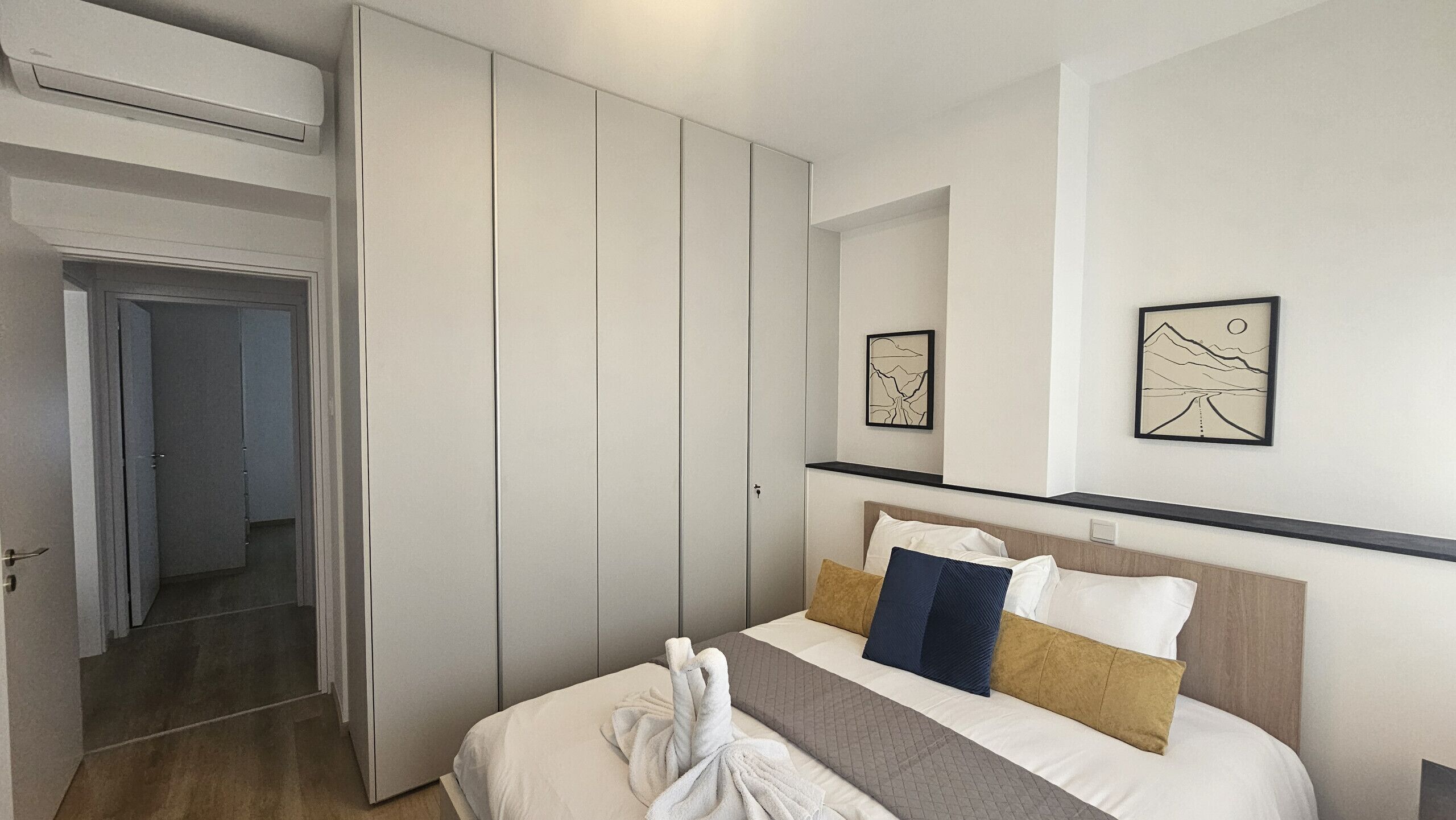 Una habitación de hotel con una cama, un armario y dos obras de arte enmarcadas en la pared.