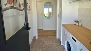 A laundry area with a washing machine, a wooden countertop, and a tiled floor. - RiverBed Rise (Tailem Bend)