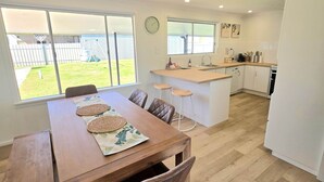 A modern kitchen with a dining area, large windows, and a view of the backyard. - RiverBed Rise (Tailem Bend)