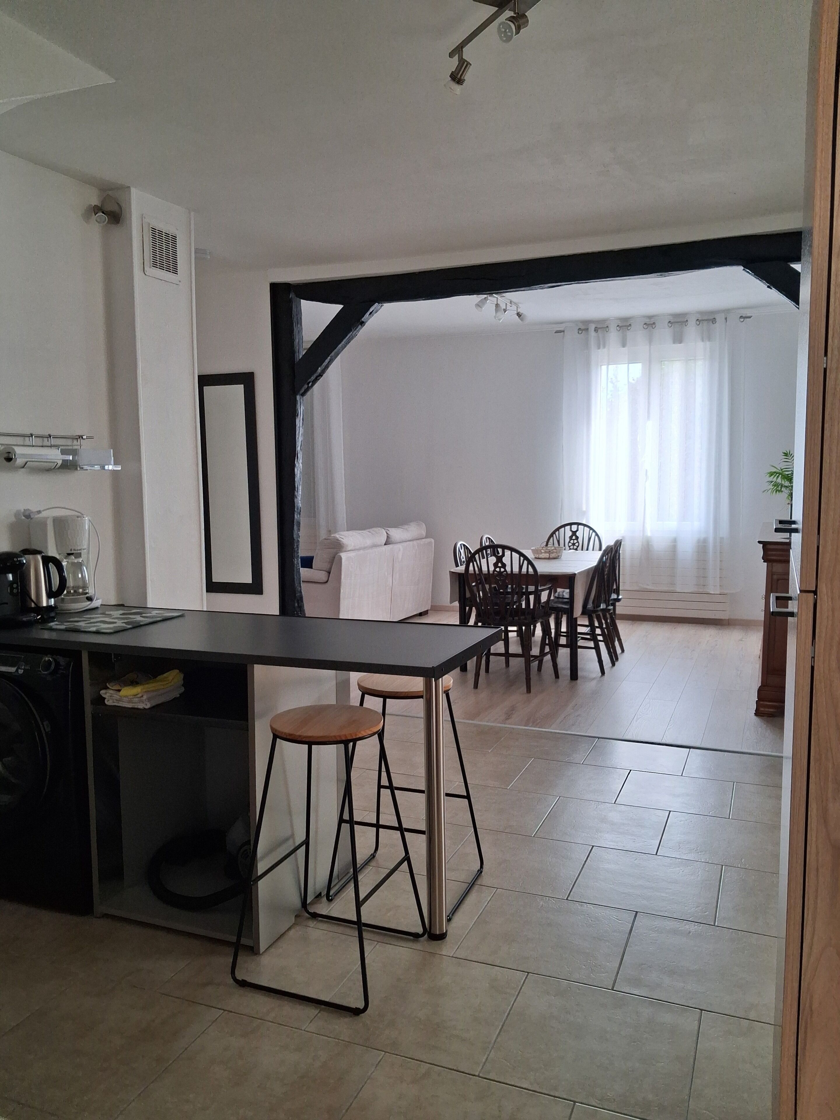 A modern kitchen with a dining area, featuring a central island, bar stools, and a dining table with chairs.