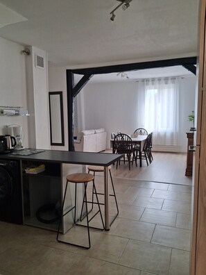 Une cuisine moderne avec un coin repas, comprenant un îlot central, des tabourets de bar et une table à manger avec des chaises.