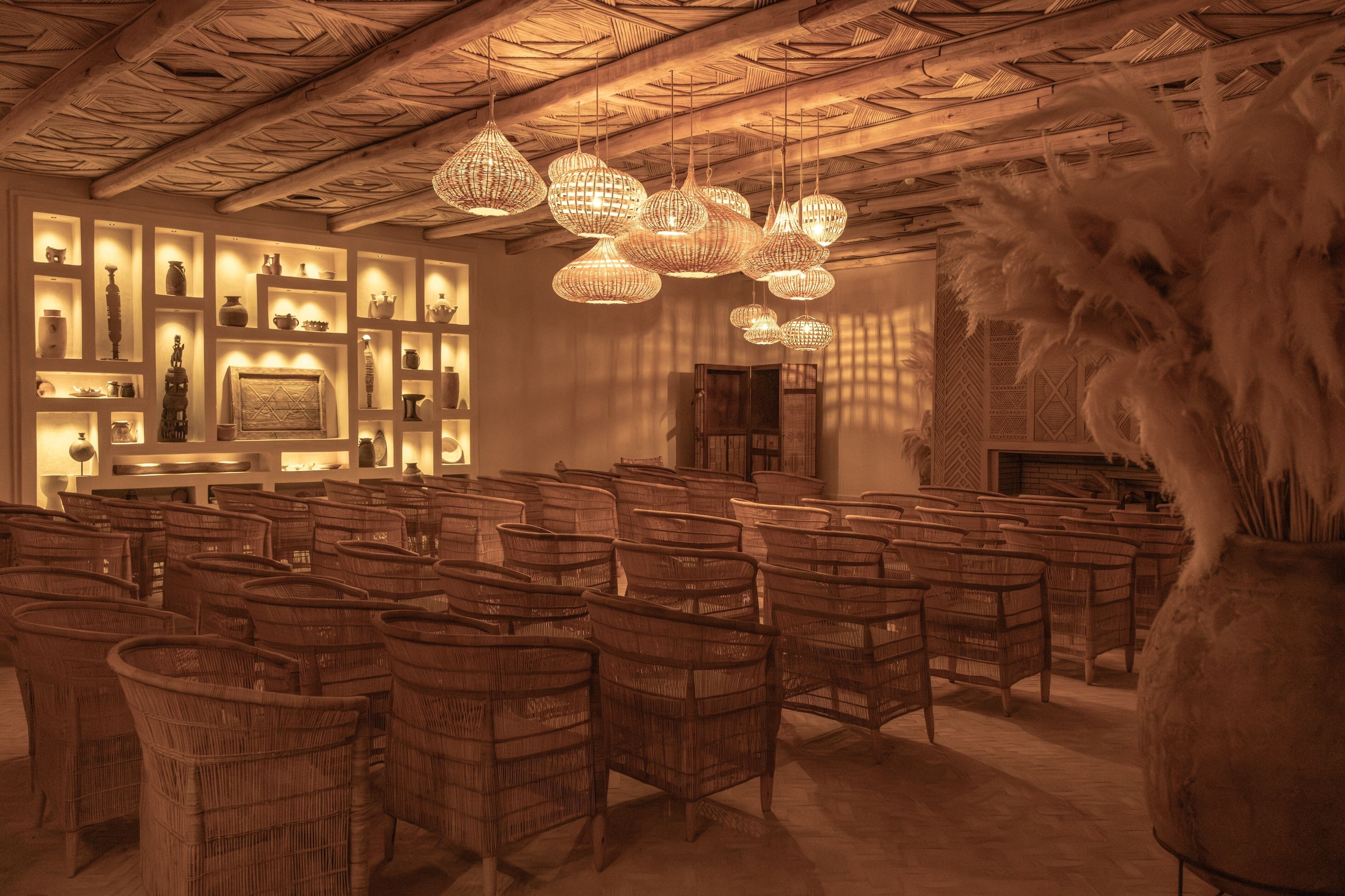 A room with wicker furniture, hanging wicker chandeliers, and shelves with various items.