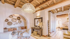 Un vaste espace de vie doté d’un haut plafond en bois, d’un grand luminaire tressé et de diverses assiettes décoratives accrochées au mur.