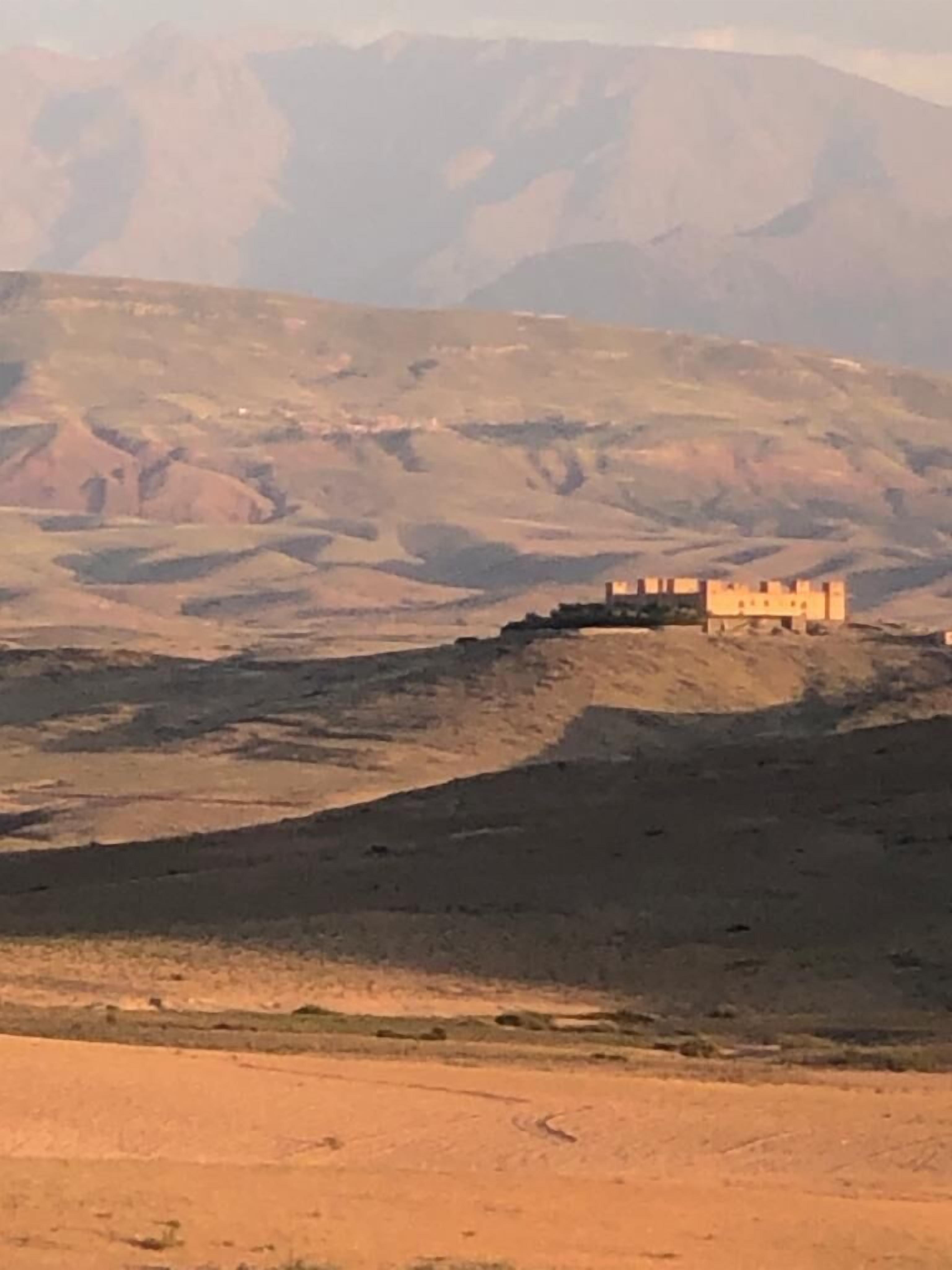 Un paysage désertique avec un petit bâtiment isolé, situé sur une colline.