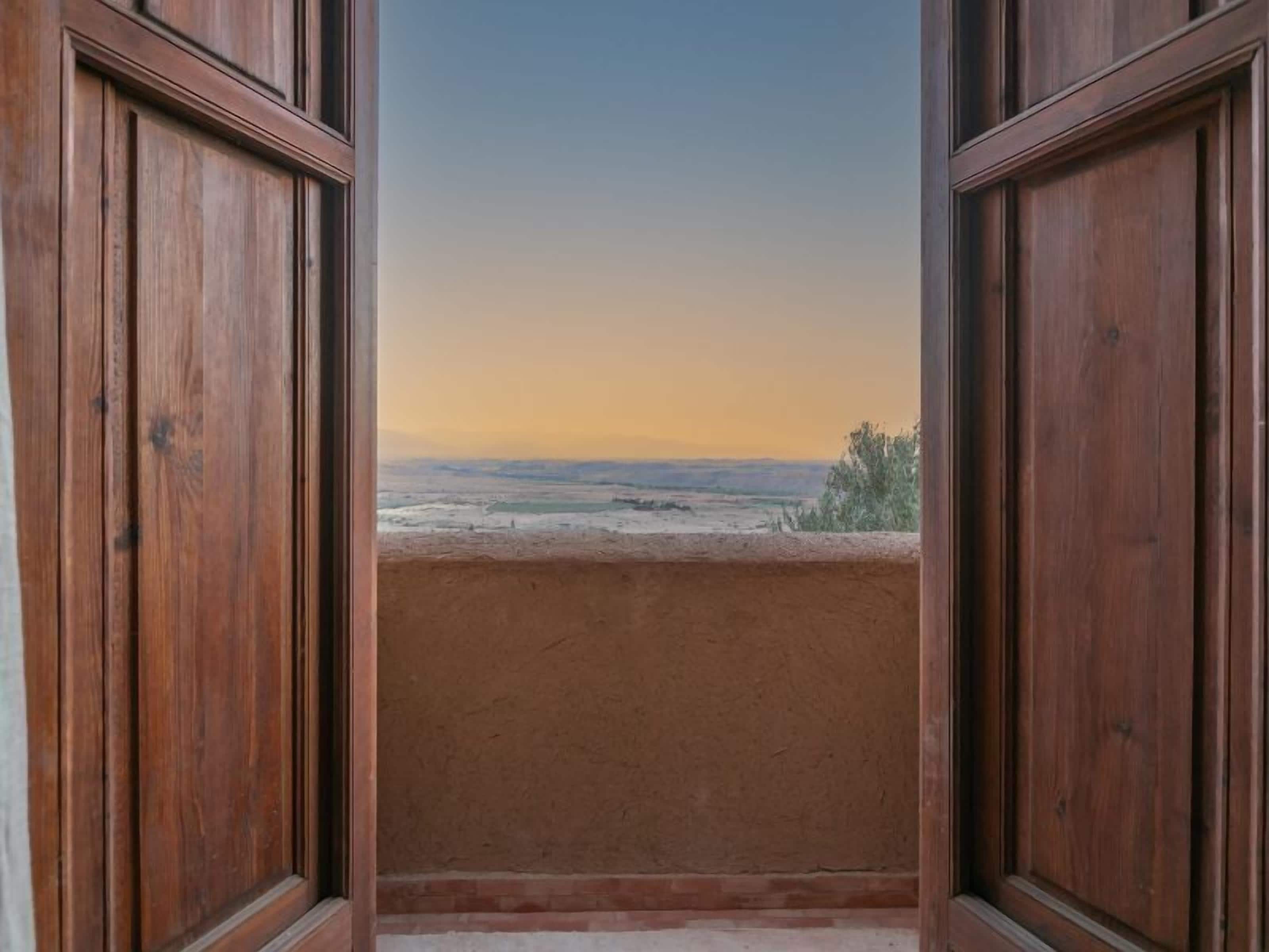 Blick durch ein Holzfenster auf eine weite Landschaft.