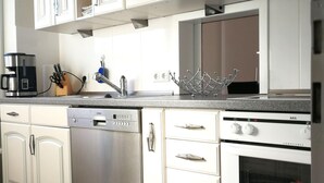 Eine moderne Küche mit weißen Schränken, Edelstahlgeräten und einer Arbeitsplatte aus Granit.