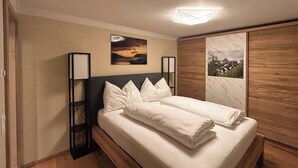 Un lit bien fait, avec du linge de lit blanc, une tête de lit en bois et deux lampes fixées au mur.