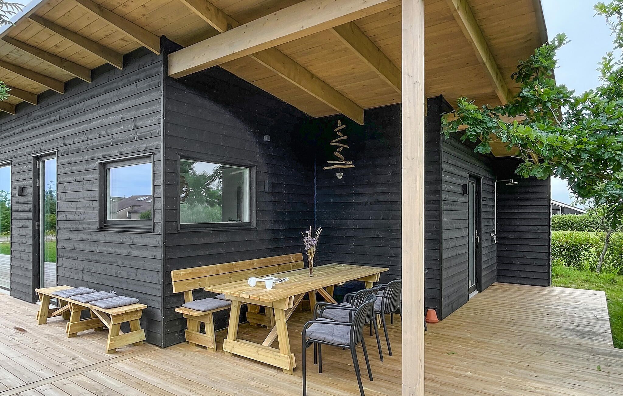 A wooden cabin with a deck, a table, and benches.
