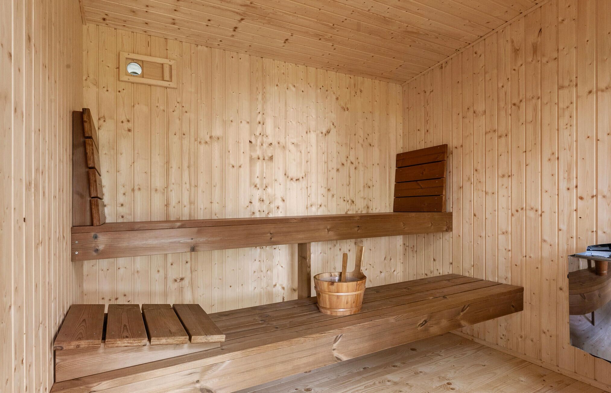 Een houten sauna met banken en een emmer.