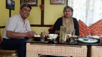 Two people sitting at a table with various dishes and glasses.