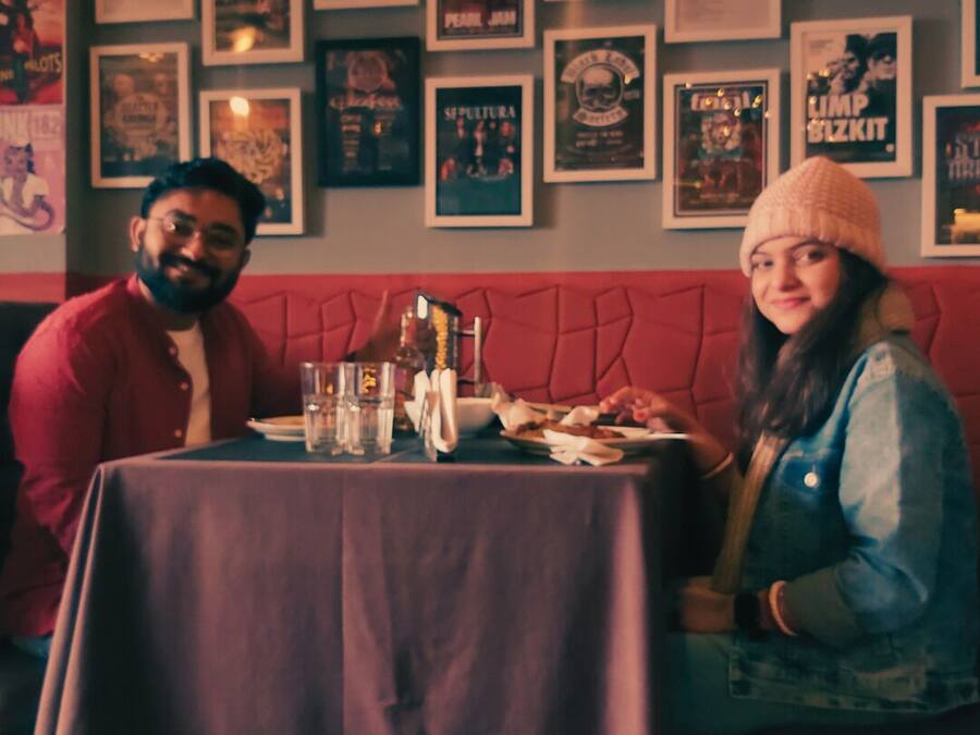 A restaurant with a red cushioned bench seating, a table with a purple tablecloth, and various framed posters on the wall.
