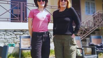 Two people standing in front of a building with a stone wall and a metal gate.