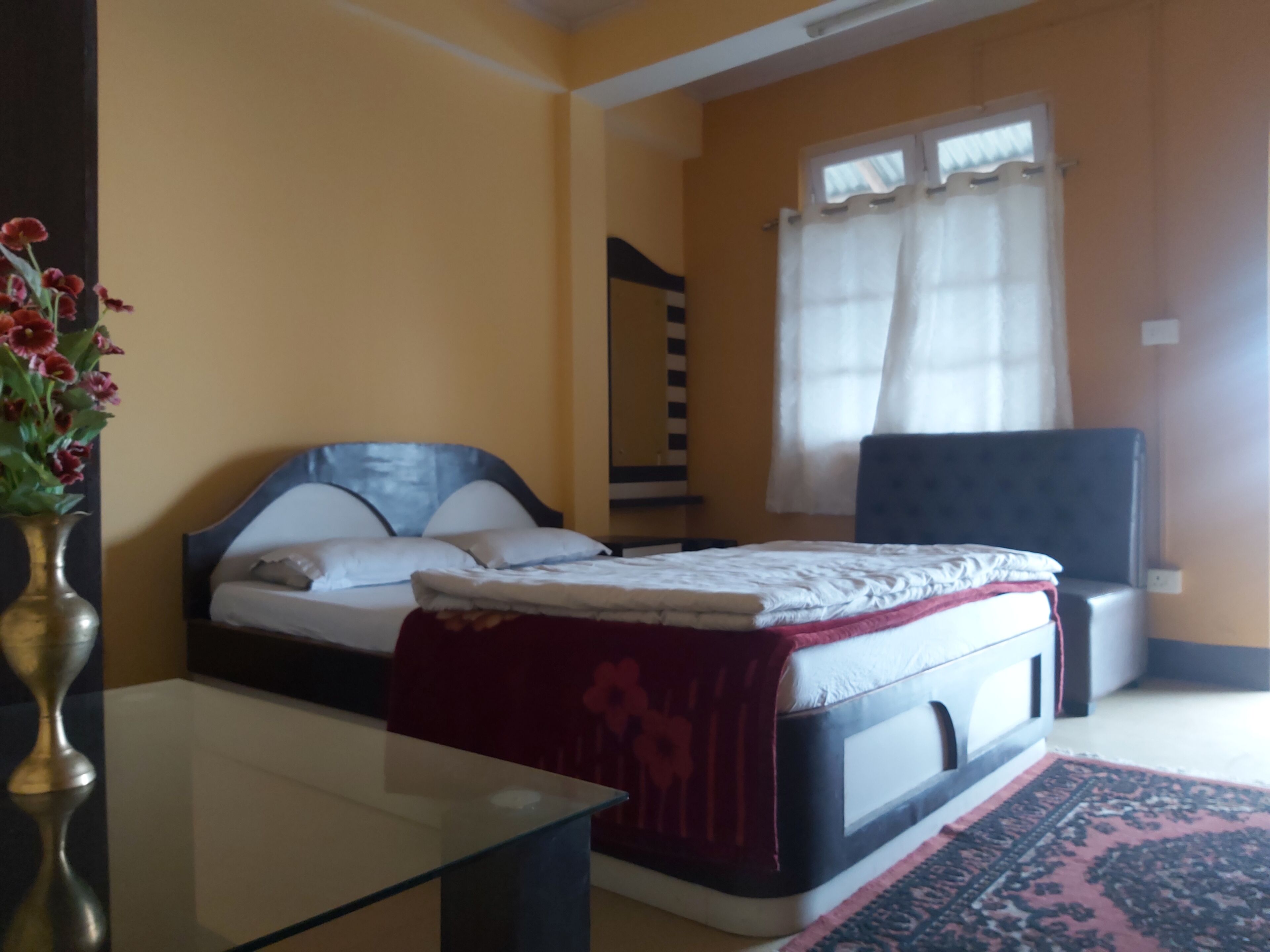 A bedroom with a bed, bedside table, and a window with curtains.