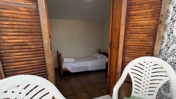 Une petite pièce avec un lit, une table et deux chaises.