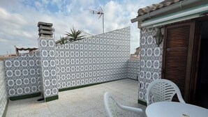 Une terrasse avec des carreaux décoratifs, une table blanche et une chaise blanche.