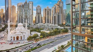 A cityscape with modern high-rise buildings and a mosque with a minaret.