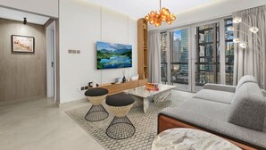 A modern living room with a sofa, coffee table, and TV. There is a balcony with a view of the city.