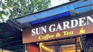A group of people seated at a table outside a coffee shop named 'Sun Garden Coffee & Tea'. - Noibai Sunflower Hotel (Hanoi)