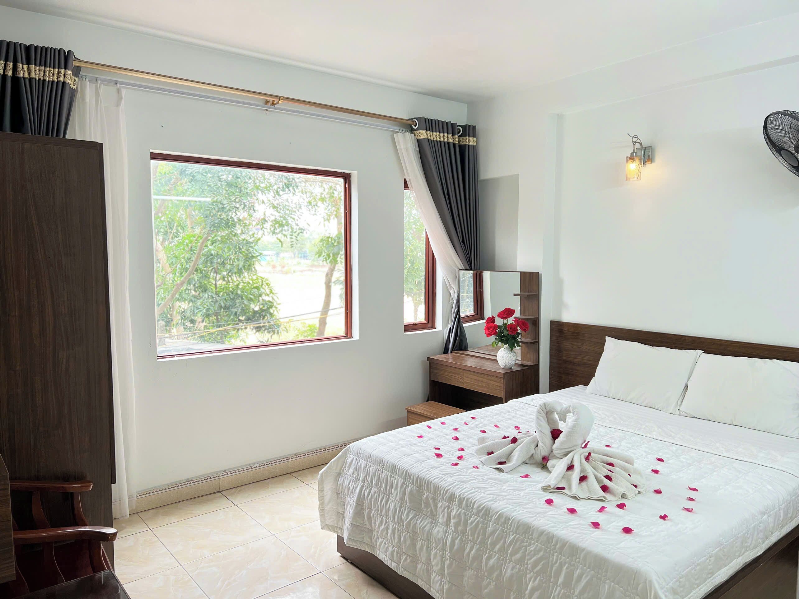 A hotel room with a bed, a nightstand, a mirror, and a window with curtains.