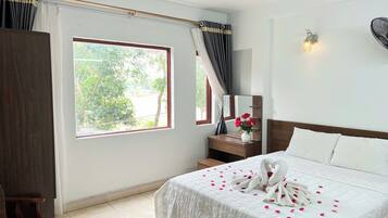 A hotel room with a bed, a nightstand, a mirror, and a window with curtains.