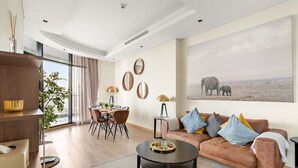 A modern living room with a dining area, a large window, and a painting of elephants.