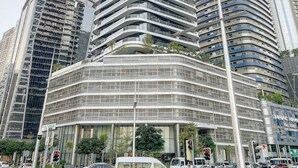 A modern high-rise building with a curved facade, surrounded by other tall buildings.