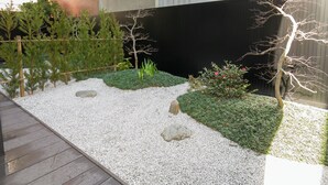 Un jardín con caminos de grava, pequeñas plantas y una terraza de madera.