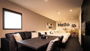 Una habitación de hotel moderna con sofá, mesa de comedor, cama y un ventanal grande.
