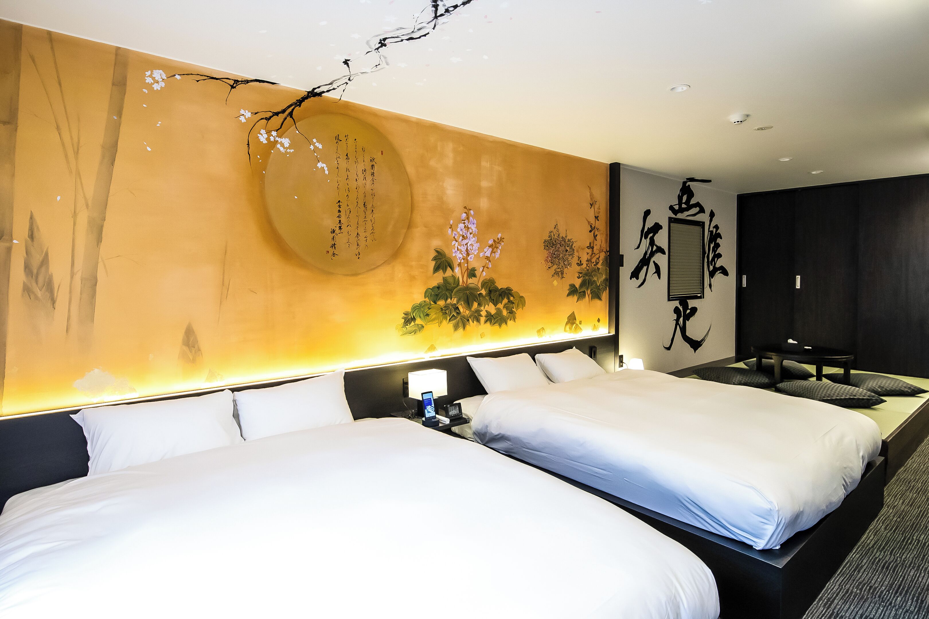 A hotel room with two beds, a large wall mural, and a desk with a phone.