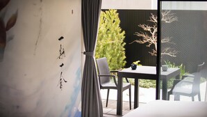 Una habitación con un ventanal amplio, una mesa con sillas y vista a un árbol.