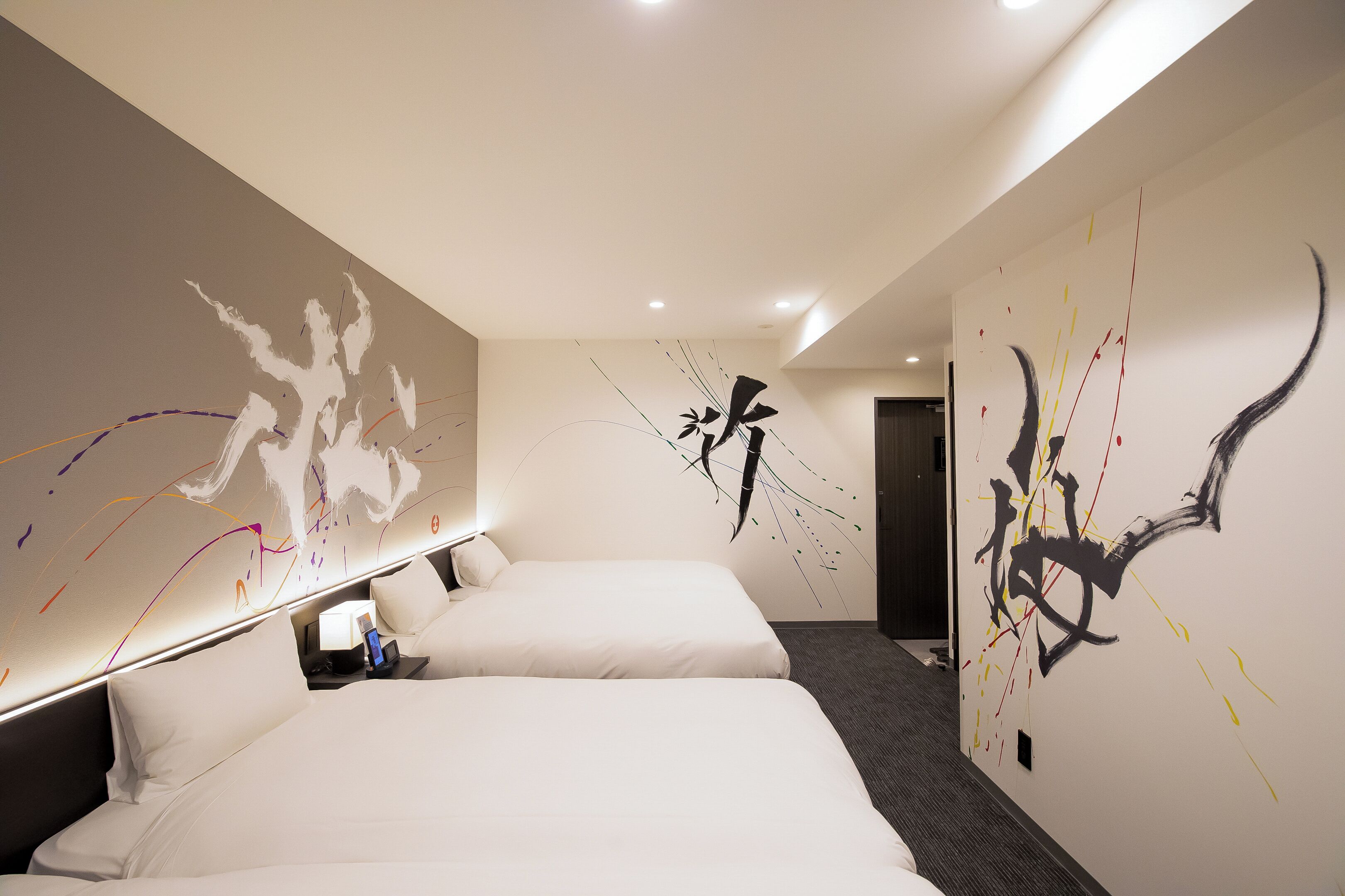 Habitación de hotel con dos camas, un cuadro abstracto de gran tamaño y un diseño moderno.