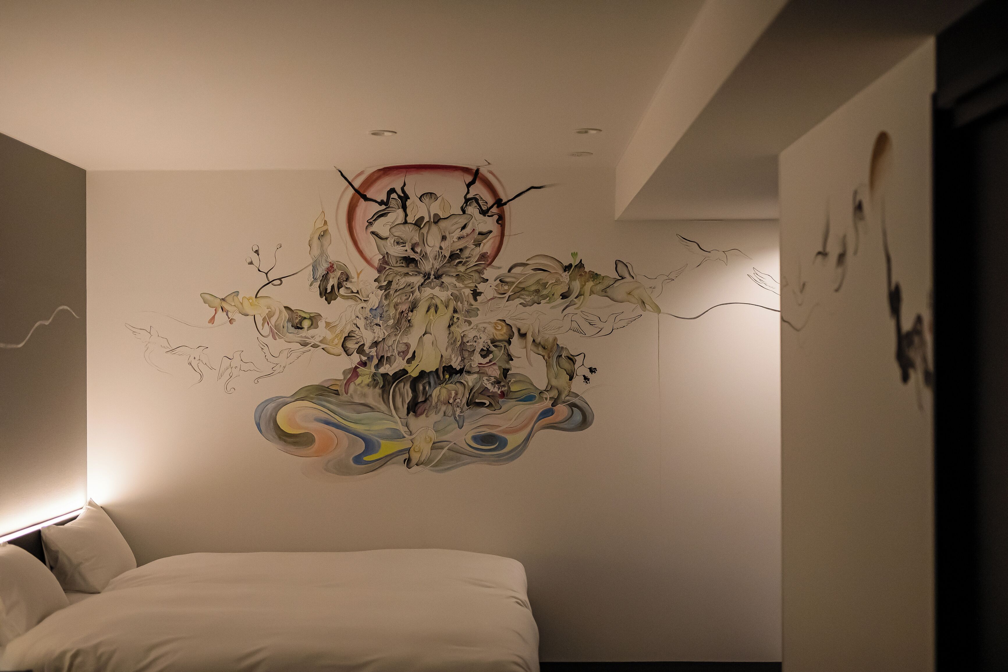 Une chambre à coucher moderne avec une grande fresque abstraite sur le mur, un lit soigneusement fait et un design minimaliste.