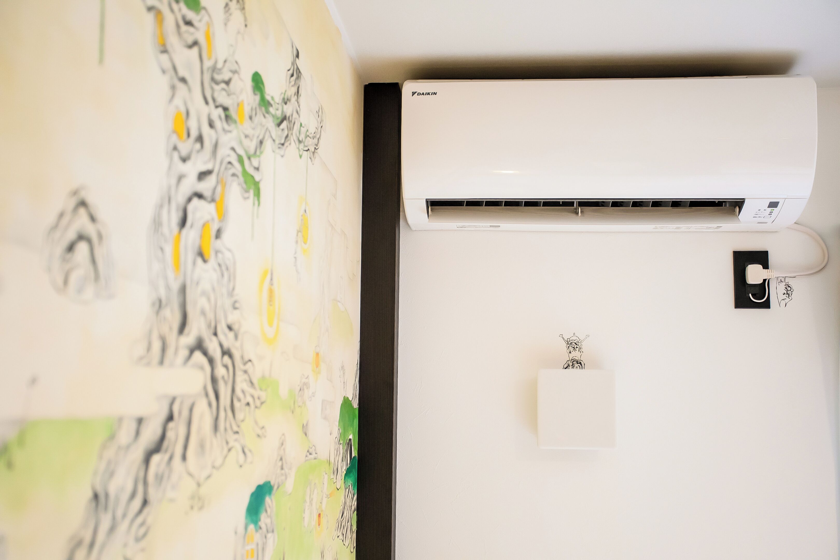 Un climatiseur Daikin fixé au mur, doté d’un panneau de commande et agrémenté d’une œuvre d’art décorative.