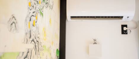 A wall-mounted Daikin air conditioner with a control panel and a wall art piece.