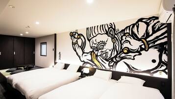 Une chambre d’hôtel avec deux lits, une grande fresque murale et une fenêtre avec des stores.